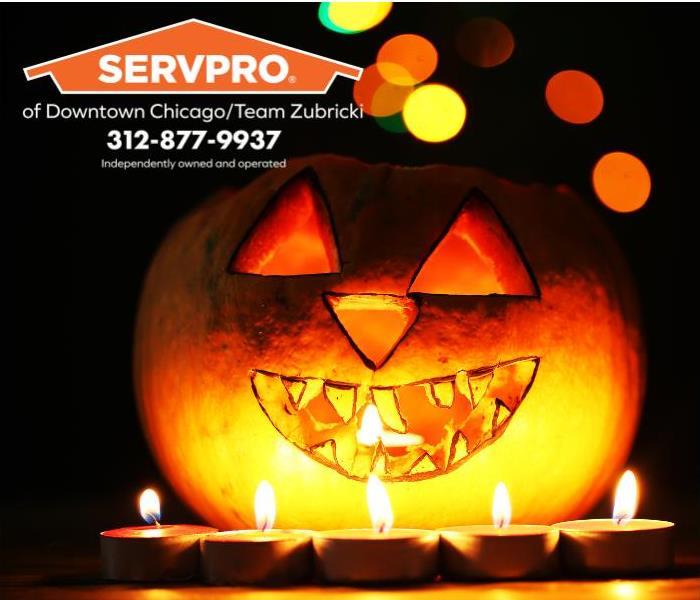 A lit jack-o-lantern is surrounded by a row of candles, casting an errie glow for a Halloween party.