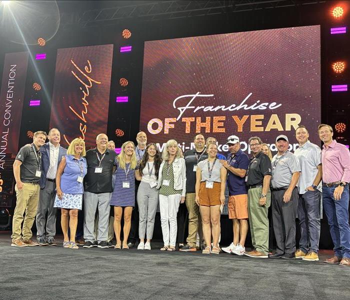 Group of people on stage including Servpro Leadership and Team Zubricki receiving an award